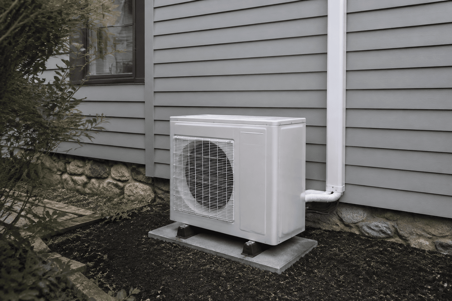 Outdoor heat-pump unit and pipework beside a home